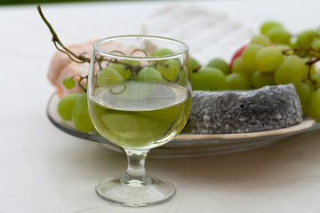 Various sorts of cheese, grapes and glass of the white wine