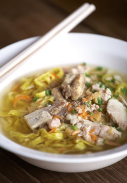 yellow thai pork noodle and pork soup on wooden table