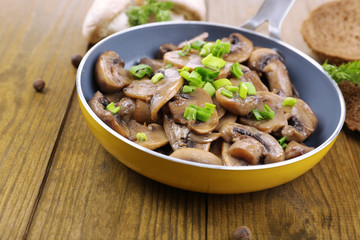 Delicious fried mushrooms in pan on table close-up
