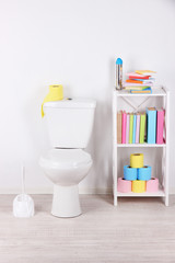 Naklejka na ściany i meble White toilet bowl and stand with books, on color wall
