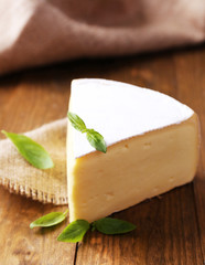 Tasty Camembert cheese with basil, on wooden table