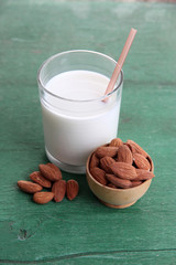 Almond milk in glass with almonds in bowl,