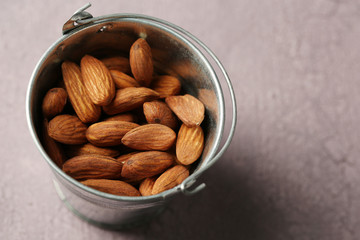 Almonds in bucket on color wooden background