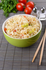Tasty instant noodles with vegetables in bowl on table close-up