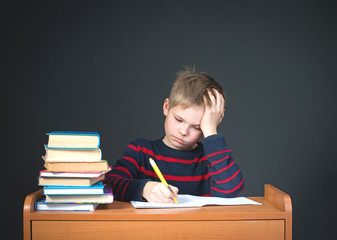 Child with learning difficulties. Tired boy doing homework.