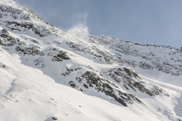 Fototapeta na wymiar Mountain ridge with wind blowing off some snow