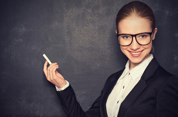 business woman teacher with glasses and a suit with chalk   at a