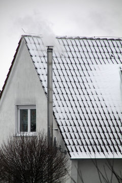 Haus mit Schnee und qualmendem Schornstein