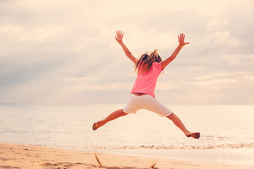 Fototapeta premium Happy Girl Jumping on the Beach at Sunset