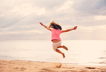 Fototapeta premium Happy Girl Jumping on the Beach at Sunset