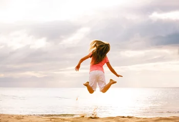 Fotobehang Happy girl jumping on the beach Sunset © EpicStockMedia