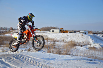 Motorcycling rider on the bike jumps from a hill on a snowy high