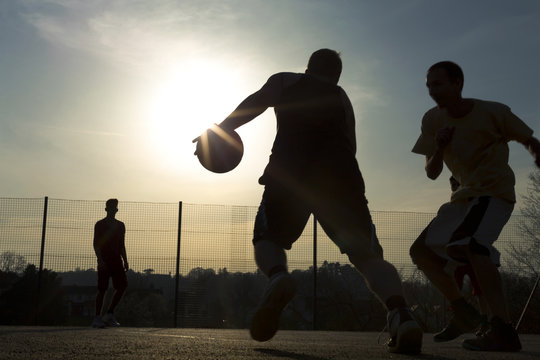 Basketball player silhouettes playing outdoors