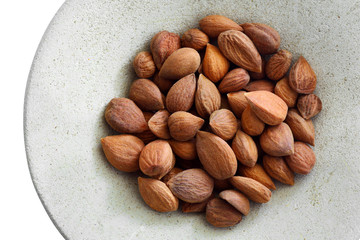 Apricot kernels on a round plate isolated on white background