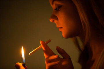 Fototapeta premium Young woman with lighter lighting up cigarette. Girl smoking.
