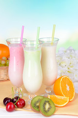 Milk shakes with fruits on table on light blue background