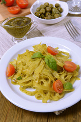 Delicious pasta with pesto on plate on table close-up