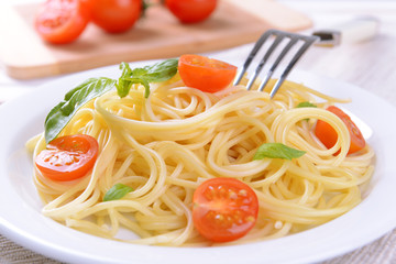 Delicious spaghetti with tomatoes on plate on table close-up