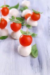 Tasty mozzarella cheese with basil and tomatoes, on wooden