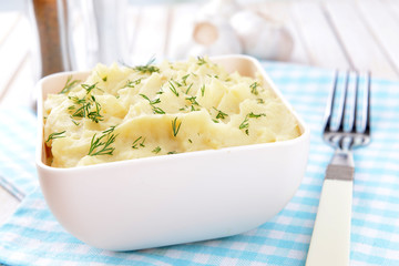 Delicious mashed potatoes with greens in bowl on table close-up