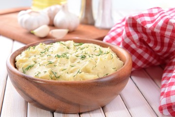 Delicious mashed potatoes with greens in bowl on table close-up