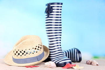Pair of colorful gumboots and hat on bright background