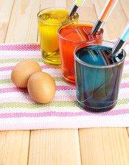 Glasses with paint for Easter eggs and eggs, close up