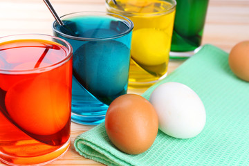 Glasses with paint for Easter eggs and eggs, close up