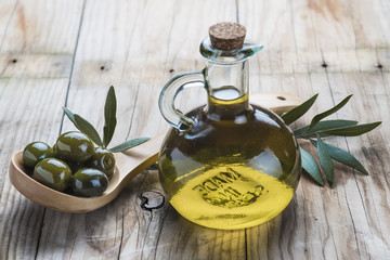 Aceite de oliva virgen y aceitunas en cuchara de madera