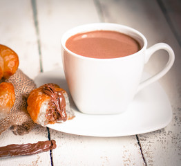Fresh baked croissants with chocolate cream and hot cocoa on woo