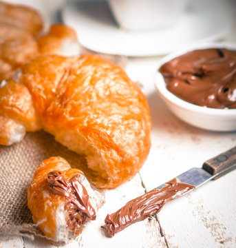 Fresh baked croissants with chocolate cream and hot cocoa on woo