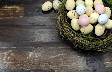 Happy Easter candy eggs in birds nest dark wood background