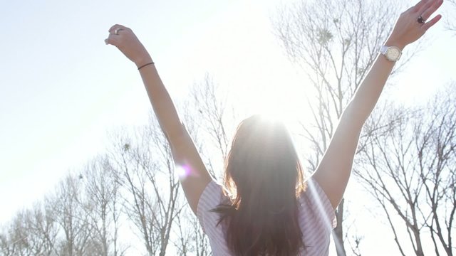 Woman in the outdoors with arms wide open under the sunlight