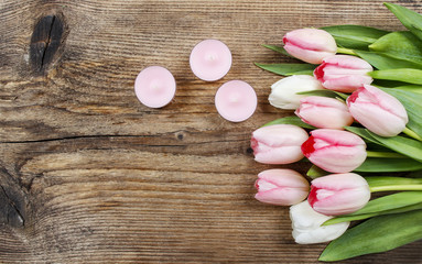 Beautiful pink and white tulips and scented candles on wooden ba
