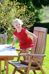Naklejka na ściany i meble Happy girl relaxing on wooden teak chair on a sunny summer day 