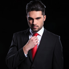 serious business man adjusts his tie