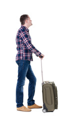 Back view of man with  green suitcase looking up.