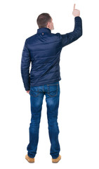 Fototapeta premium Back view of pointing young men in jacket and jeans.