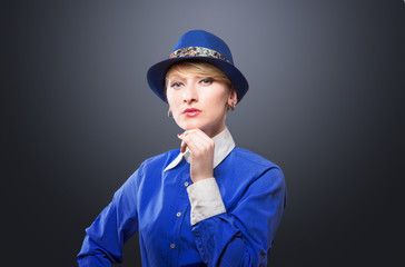 Portrait of a serious woman in a blue hat, dark background