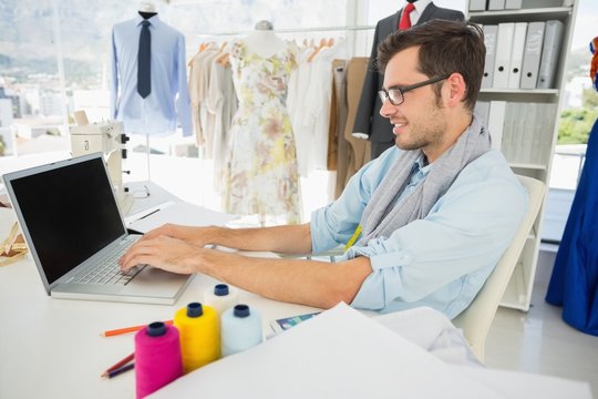Concentrated young male fashion designer using laptop