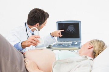 Doctor showing pregnant woman her baby on sonagram