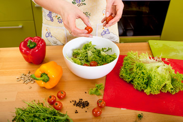 Woman preparing salad with tomatoes, pepper and avocado on the r