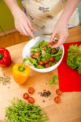Woman preparing salad with tomatoes, pepper and avocado on the r