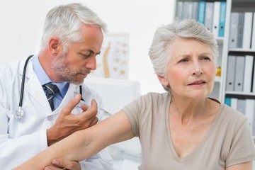 Obraz premium Male doctor injecting senior patient