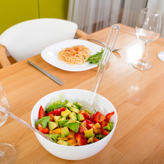 Salad on the dinner table with pasta and wine glasses