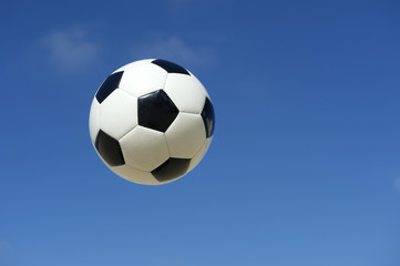 Fototapeta na wymiar Classic Black and White Soccer Ball Football Flying in Blue Sky