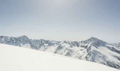 Snow covered slope with mountain ridge in the back