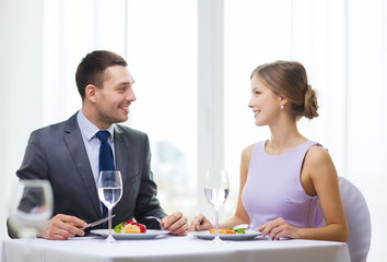 smiling couple eating main course at restaurant