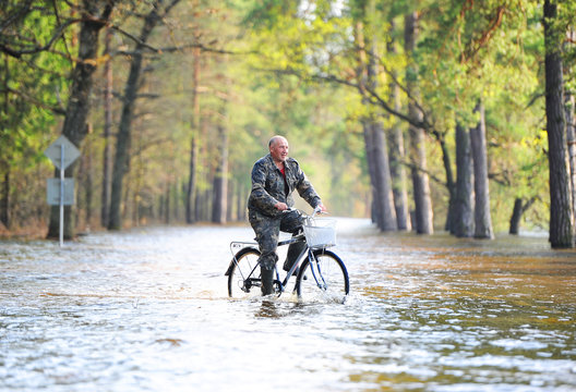 the man by bicycle goes on the flooded road