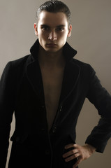 Portrait of a beautiful young man dressed in a black long coat